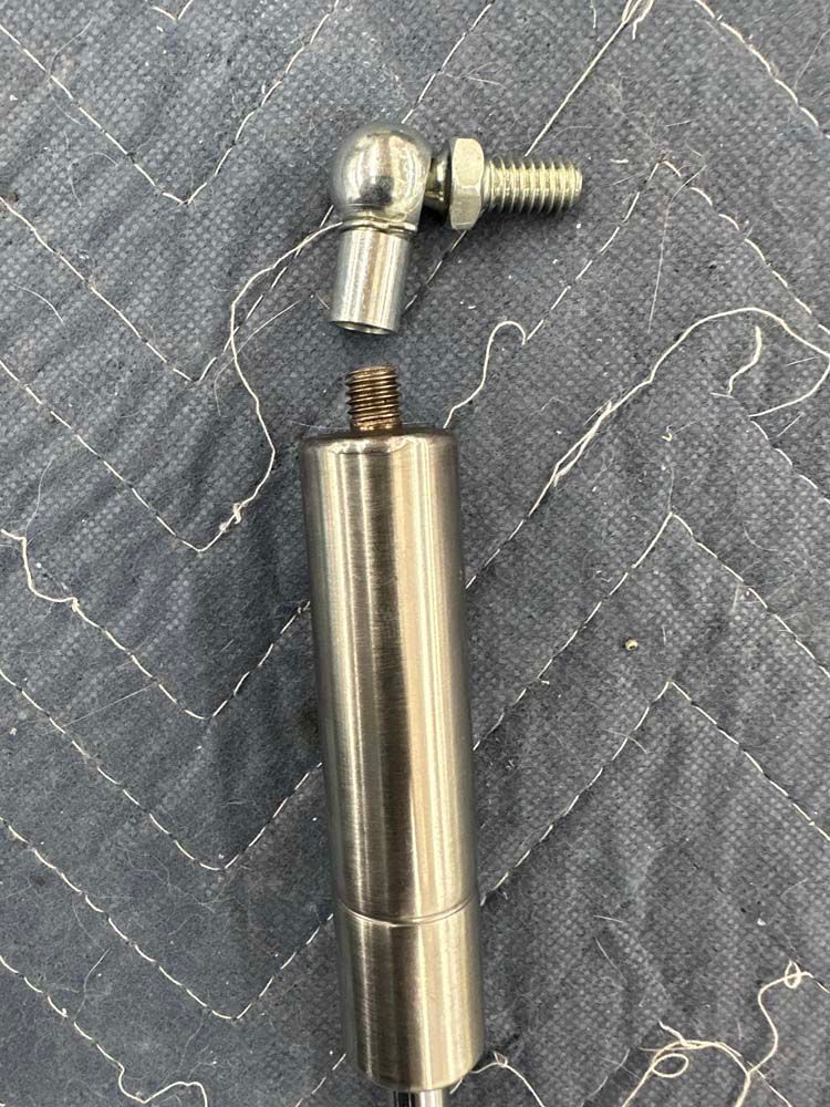 A stainless steel pipe with a screw on it is sitting on top of a quilt.