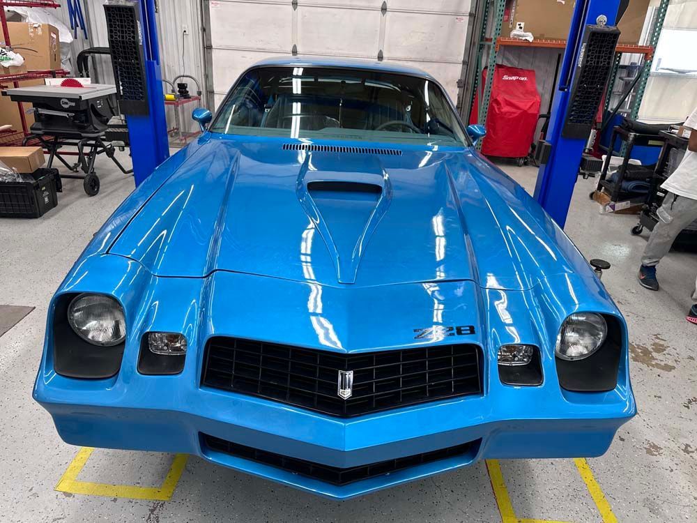 A blue car is sitting on a lift in a garage.