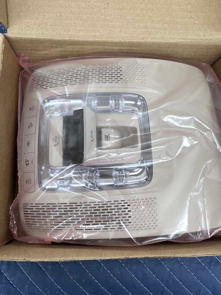 A phone is wrapped in plastic and sitting in a cardboard box.