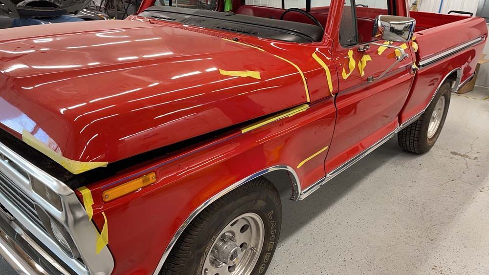 A red truck is sitting on a white floor in a garage.