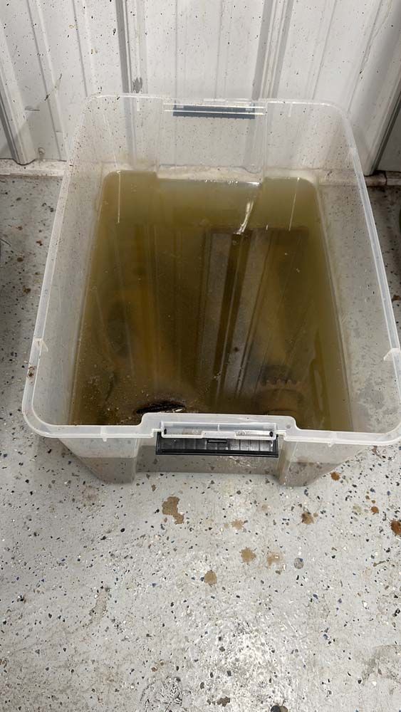 A clear plastic container filled with water and a piece of wood.