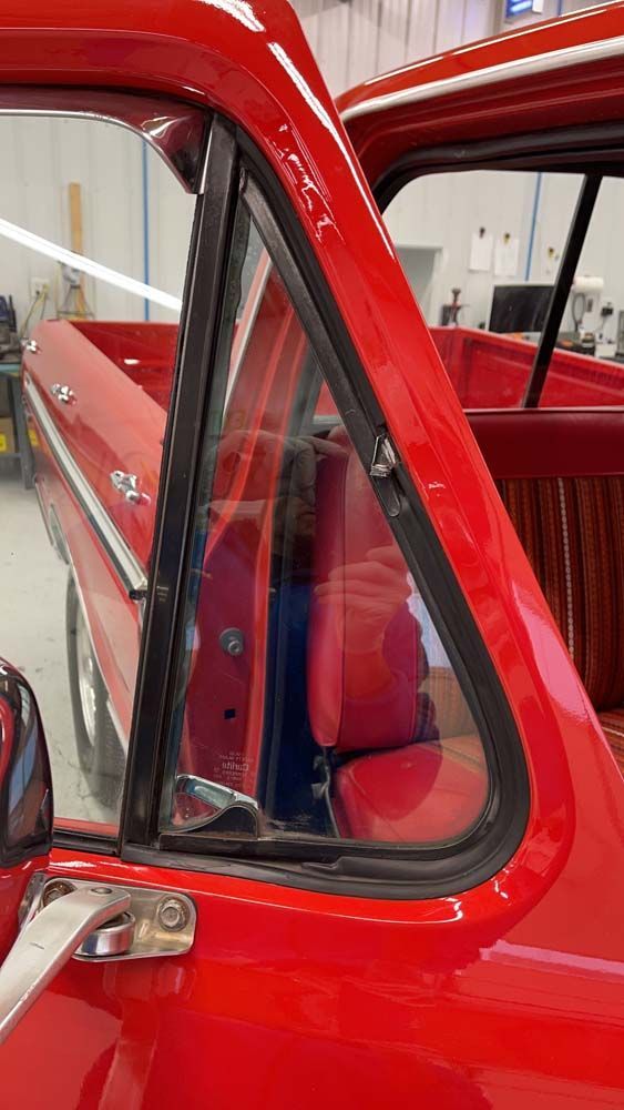 A red truck is parked in a garage with the door open.