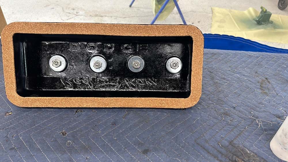 A cork box with screws in it is sitting on a blue blanket.