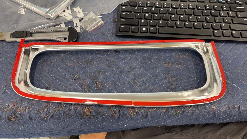 A keyboard and a chrome trim are on a table