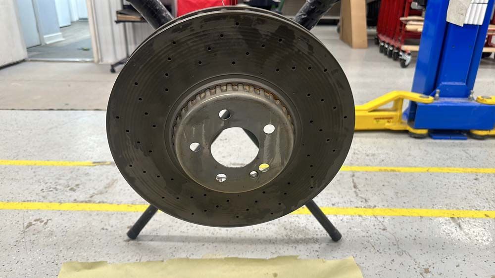 A close up of a brake disc on a stand in a garage.