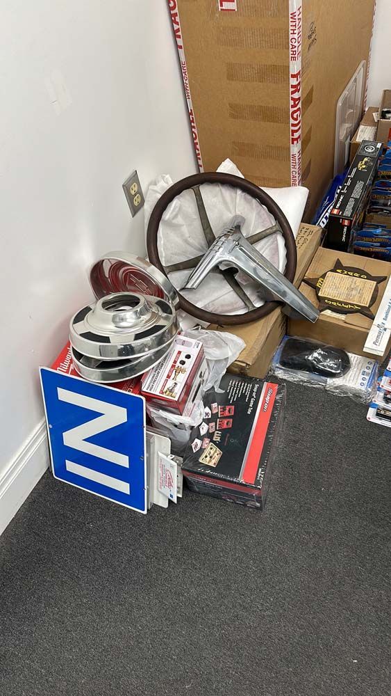 A blue sign with the letter n on it is sitting on the floor next to a steering wheel.