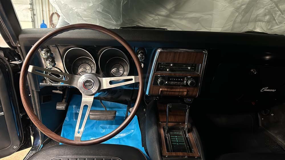 The interior of a car with a wooden steering wheel and dashboard.