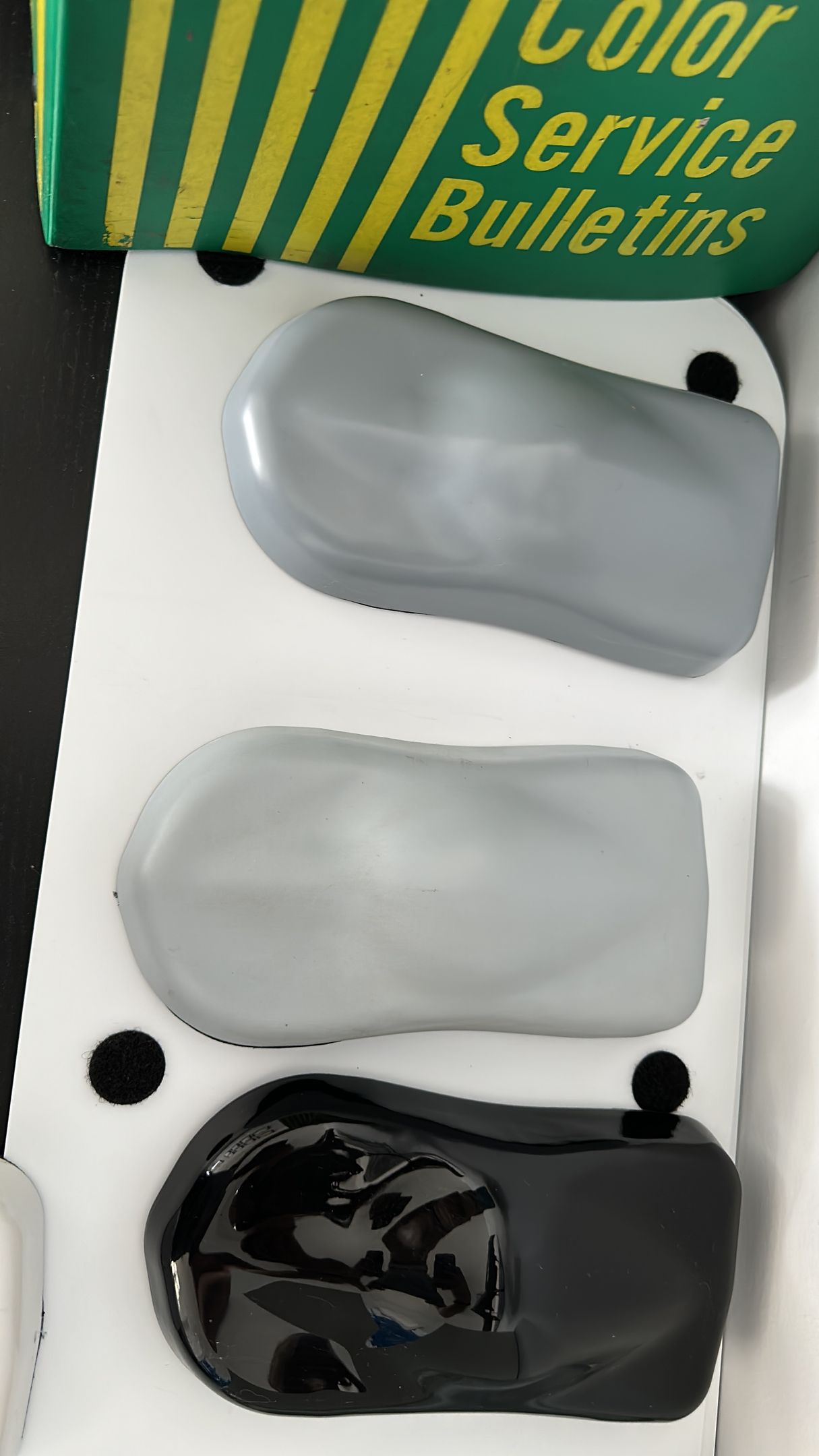 A box of color service bulletins contains three different shades of paint