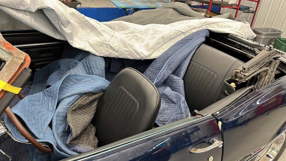 The roof of a car is open and covered in blankets.