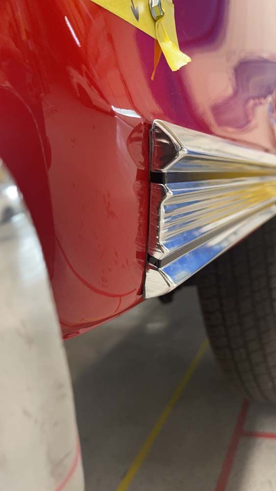 A close up of a red car with a chrome trim on the side.