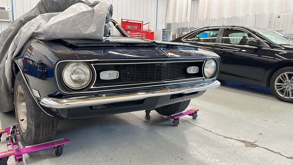 A black car is parked in a garage next to a black car.