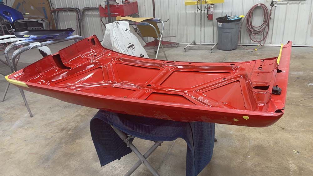 A red boat is sitting on a table in a garage.