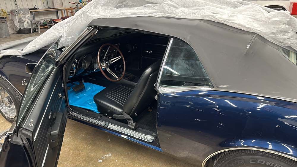 The inside of a blue convertible car with the door open.