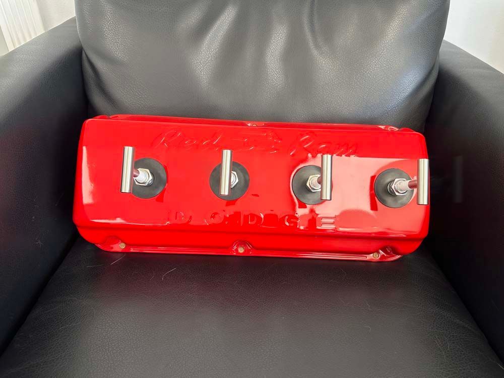 A red valve cover is sitting on a black leather chair