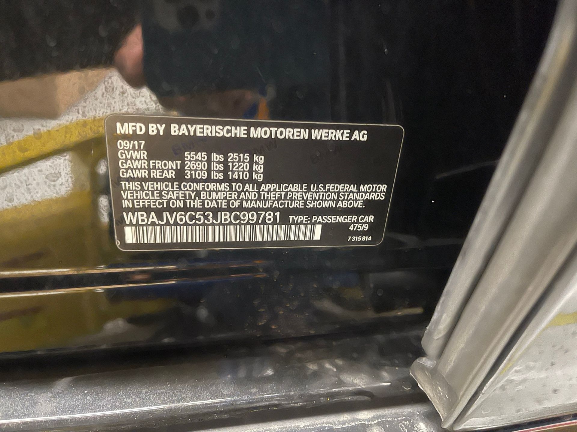 A black car has a sticker on the door that says mfd by bayerische motoren werke ag