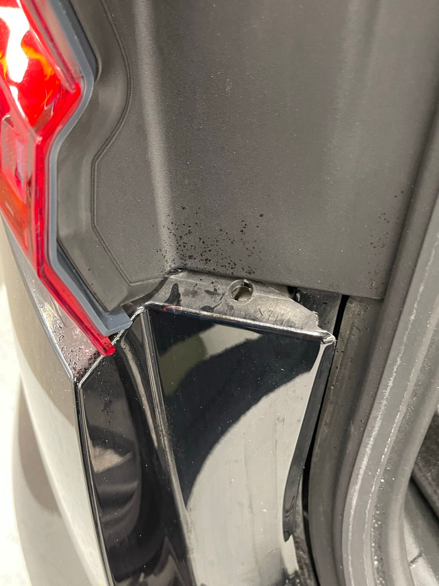 A close up of the back of a black car with a red tail light.