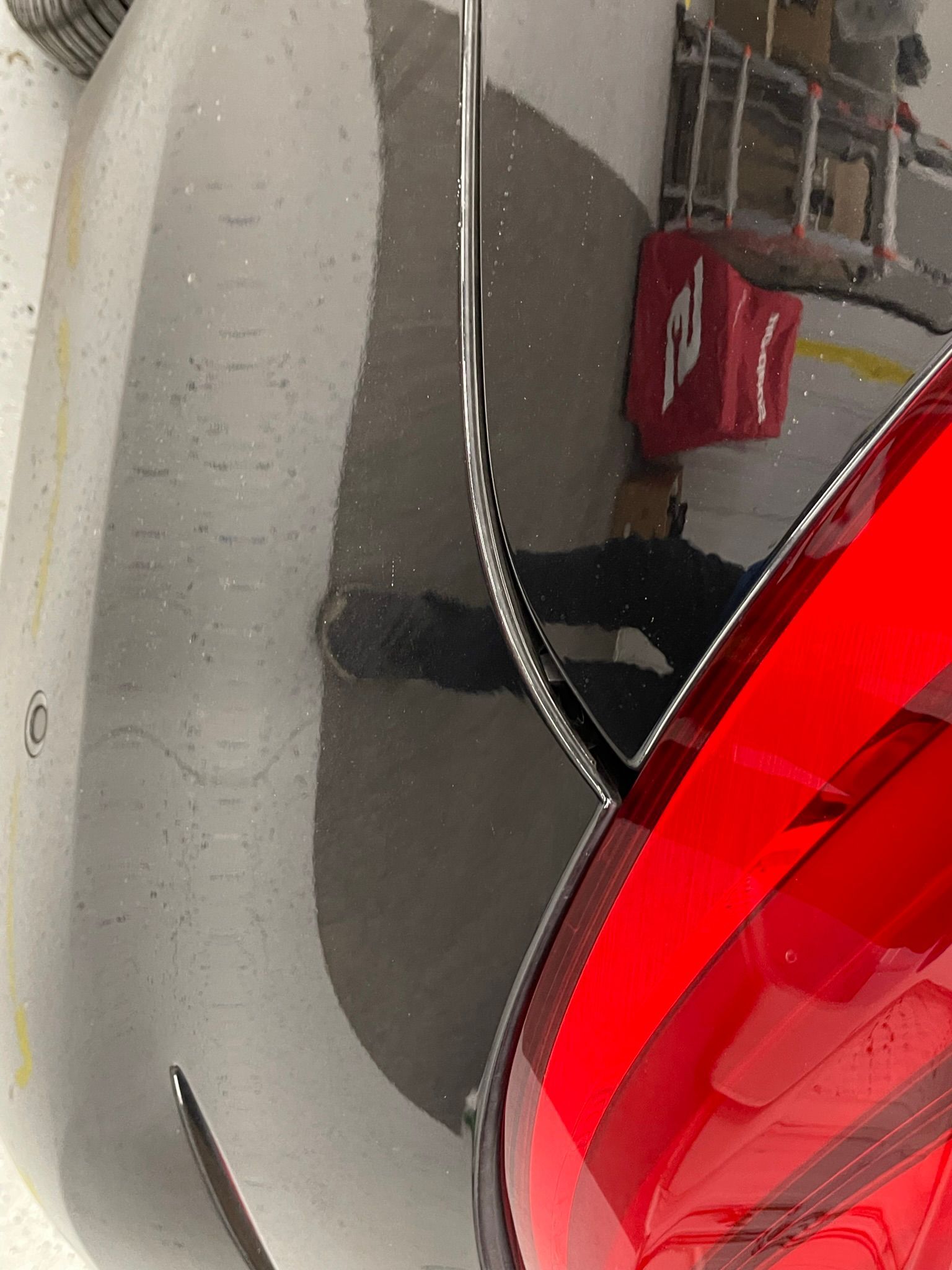 A close up of a black car with a red tail light.