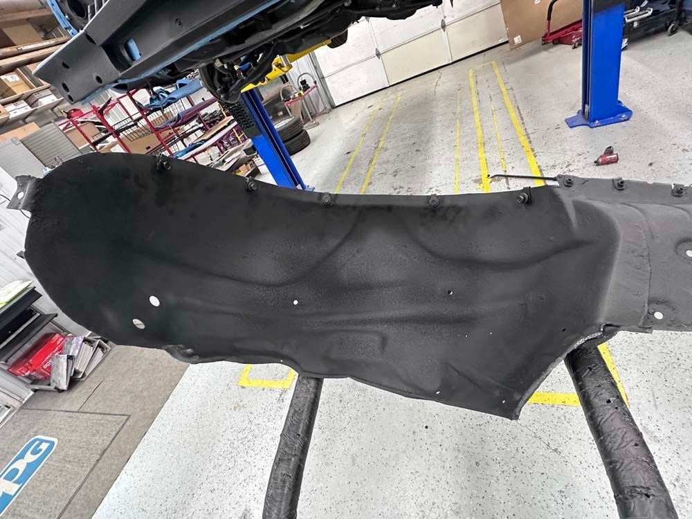 A black fender liner is sitting on a table in a garage.