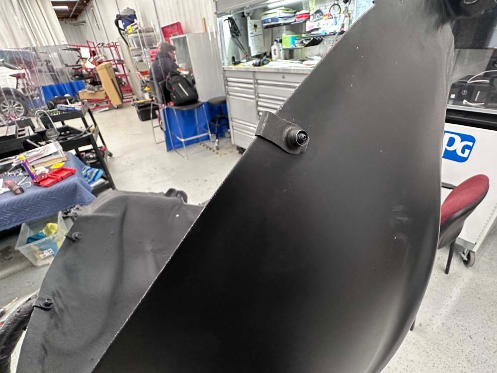 A black fender is sitting on the floor in a garage.