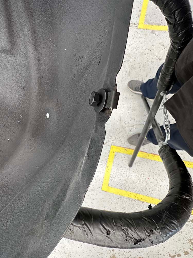 A person is standing next to a black object with a hose attached to it.