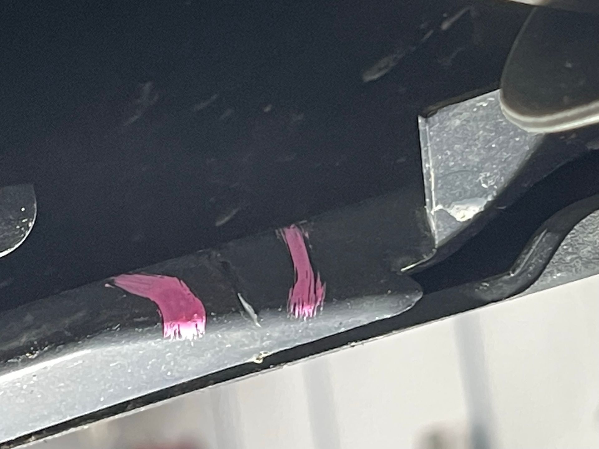 A close up of a piece of metal with pink markings on it