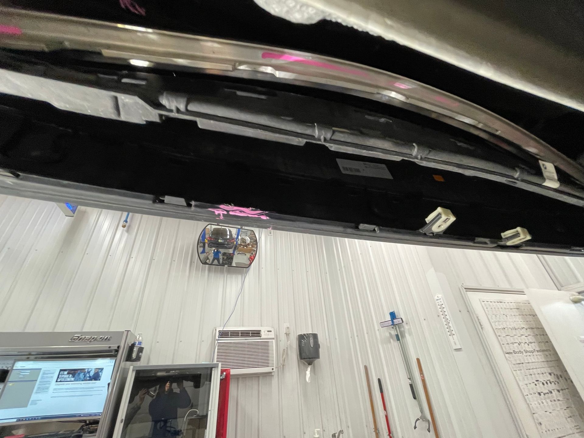 The hood of a car is being removed in a garage.