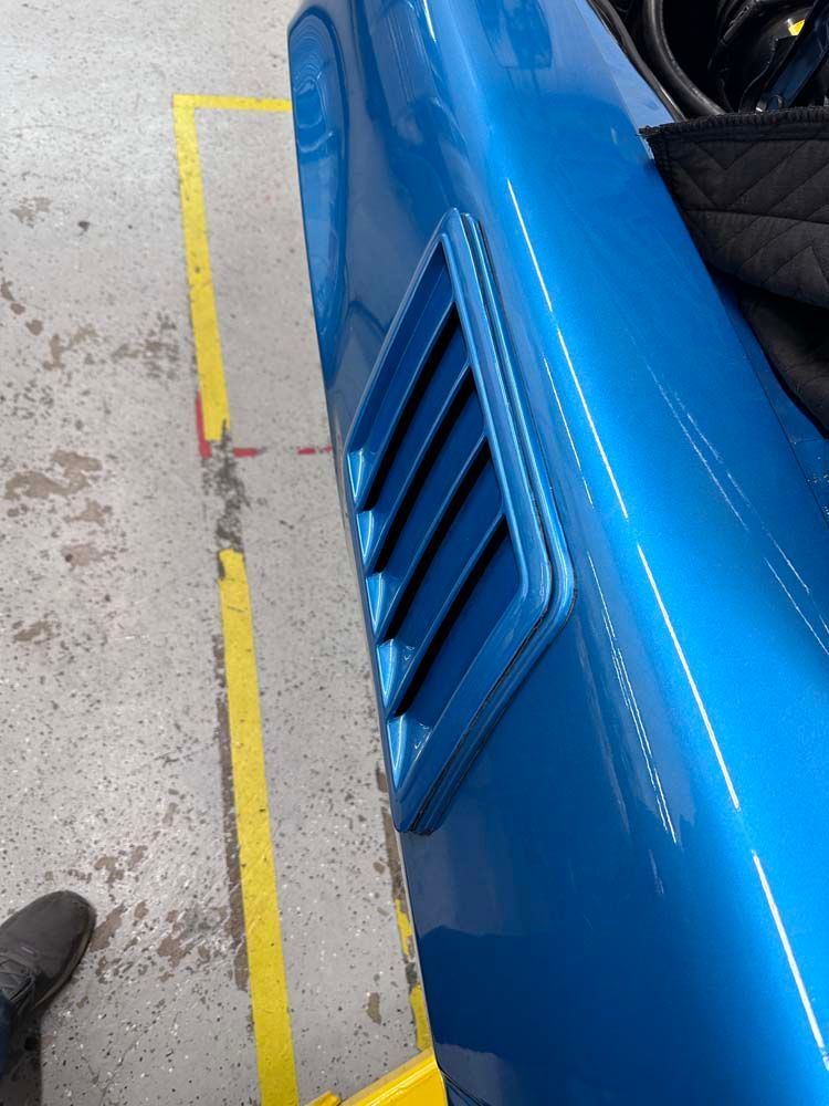 A blue car is parked next to a yellow line