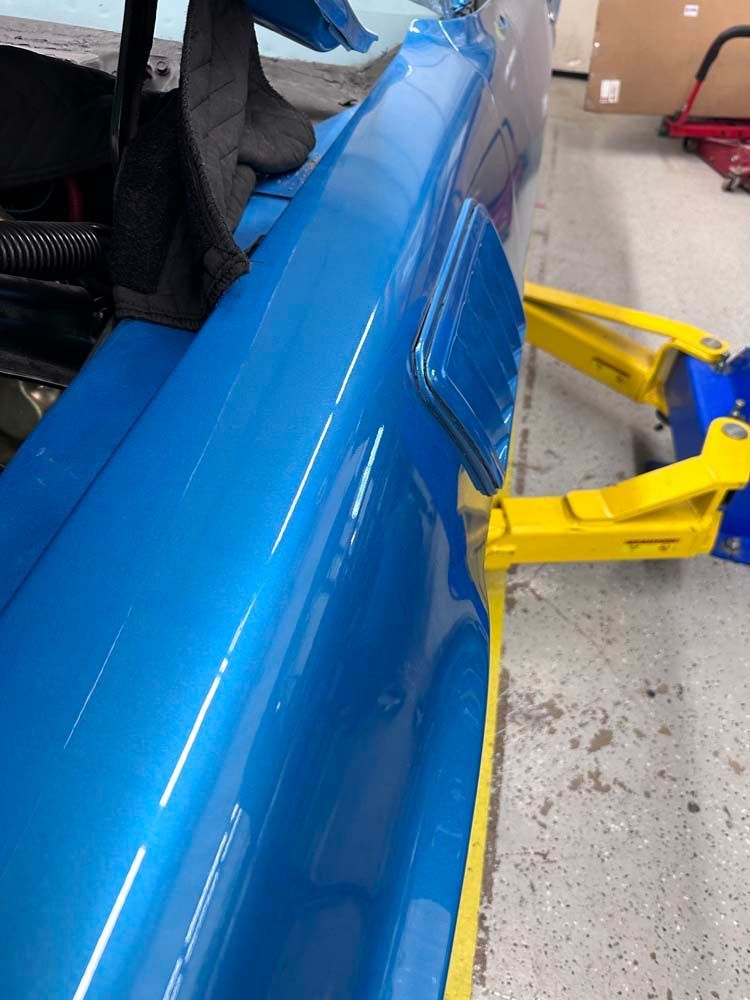 A blue car is sitting on a lift in a garage.
