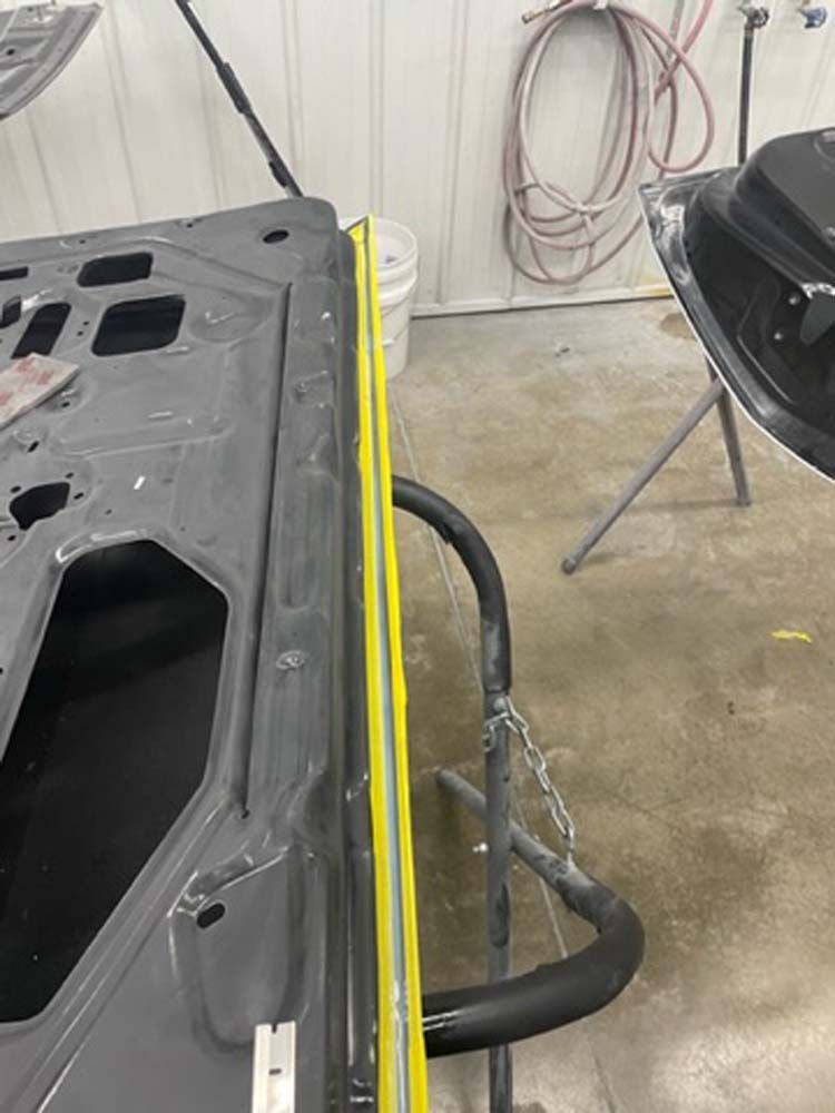 A car door is being painted in a garage.