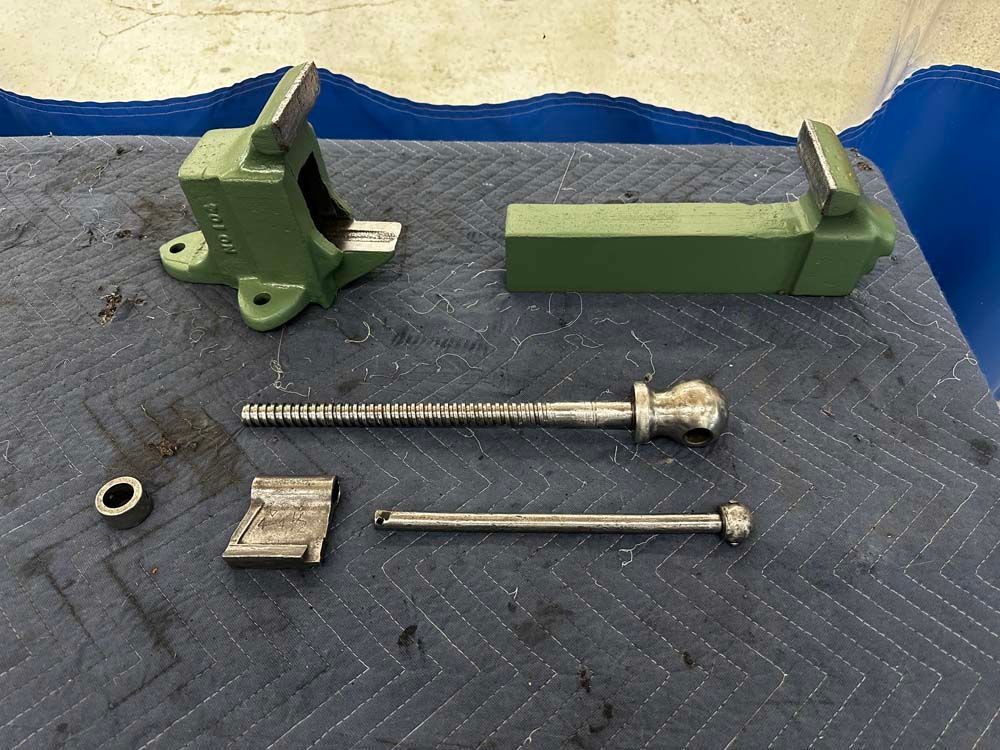 A green vise is sitting on top of a blue table.