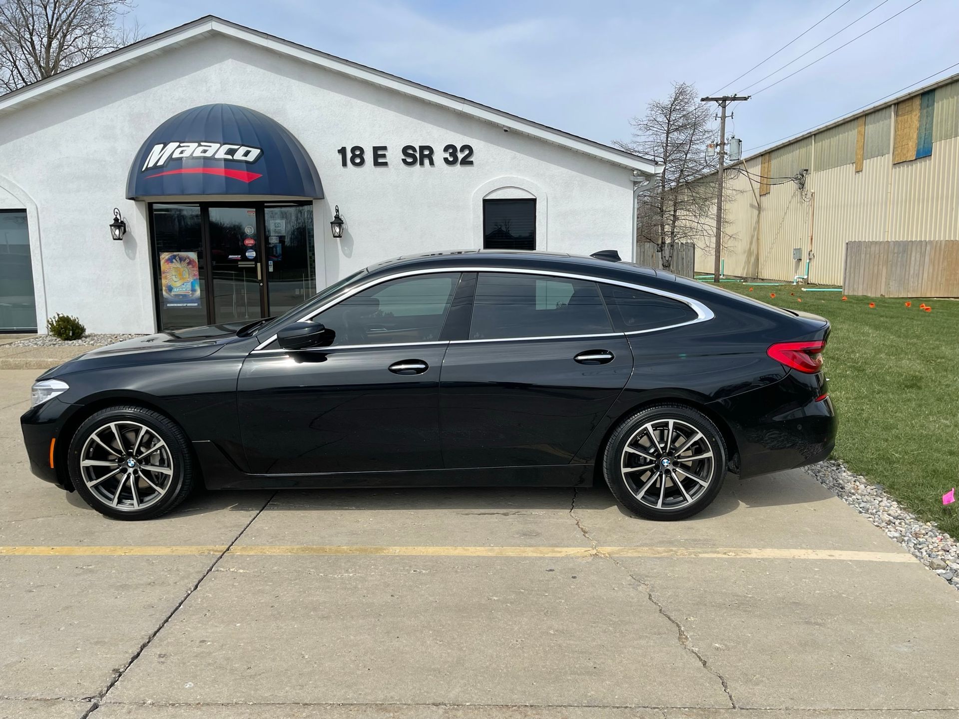 A black car is parked in front of a white building.