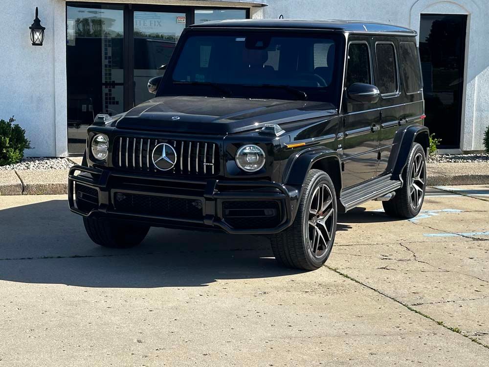 A black mercedes benz g63 amg is parked in front of a building.