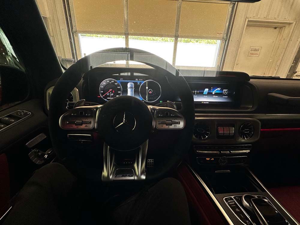 A person is sitting in the driver 's seat of a mercedes benz g63 amg.