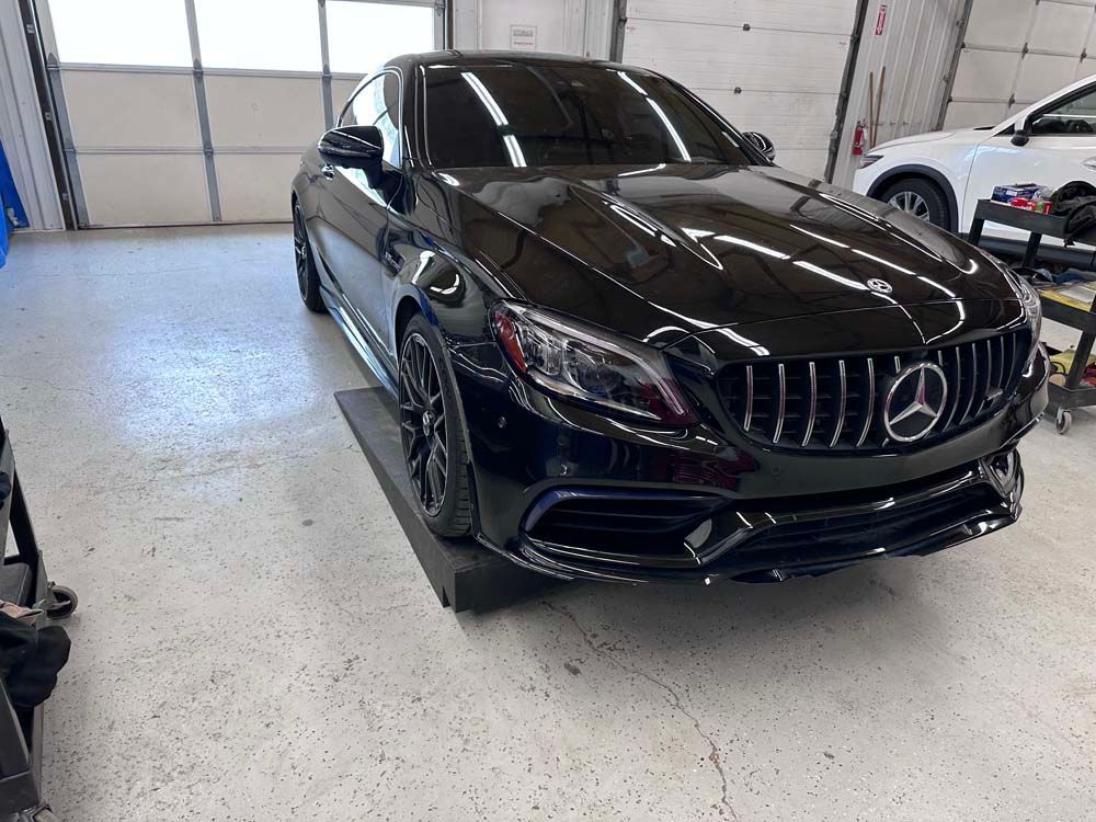 A black mercedes benz is parked in a garage.