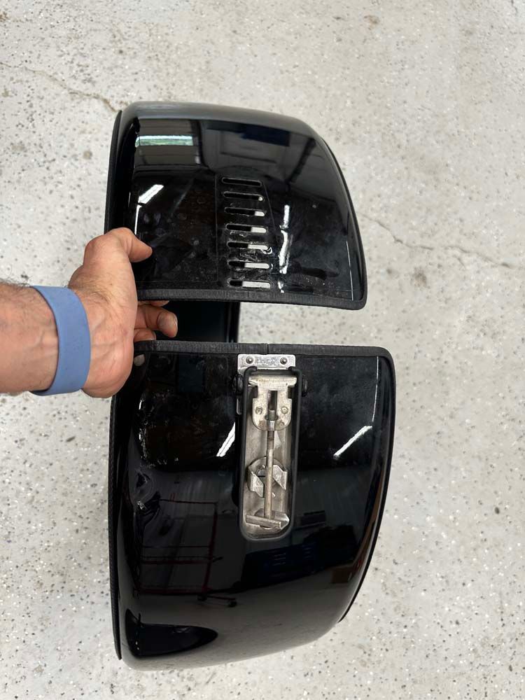 A person is holding a pair of black fender covers.