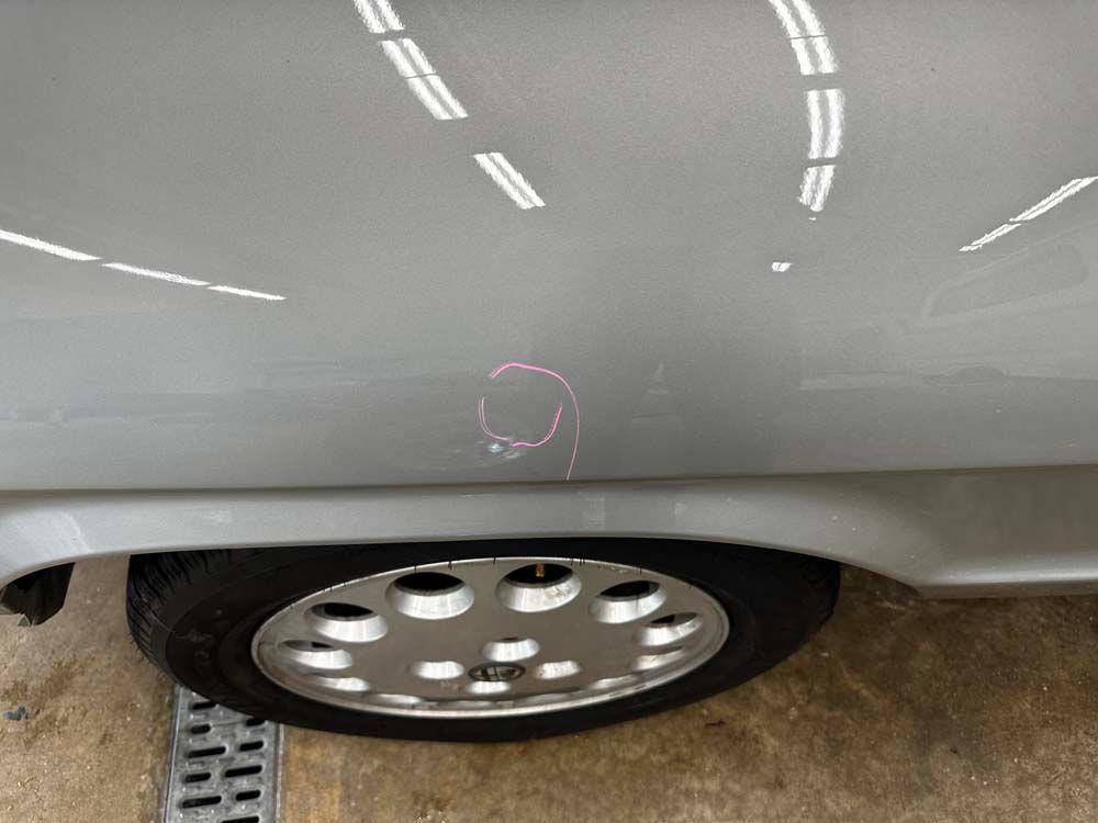 A close up of a car 's fender and tire in a garage.