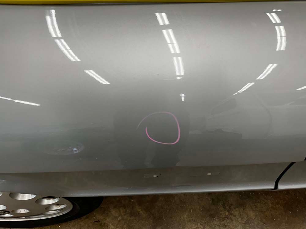 A silver car with a red circle on the side of it