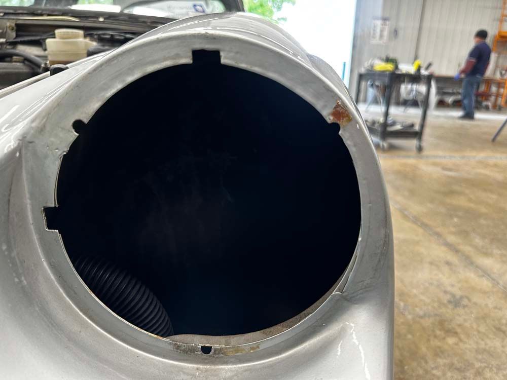 A close up of a car hood with a hole in it.