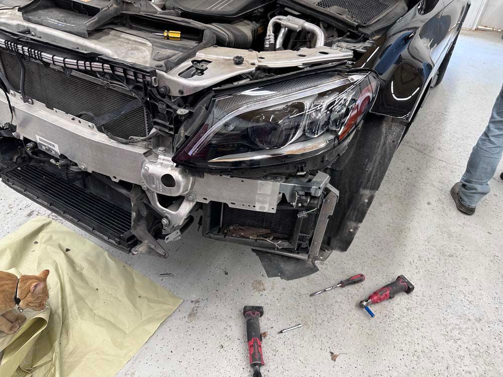 A black mercedes benz is being repaired in a garage.