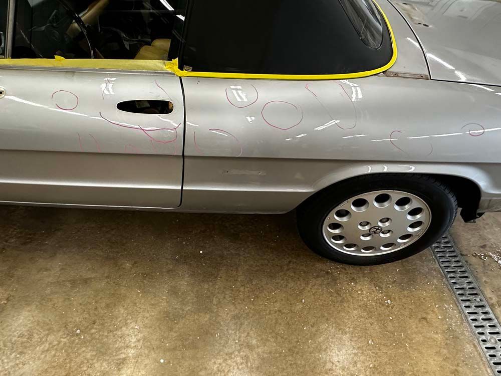 A silver car with a black top is parked in a garage.