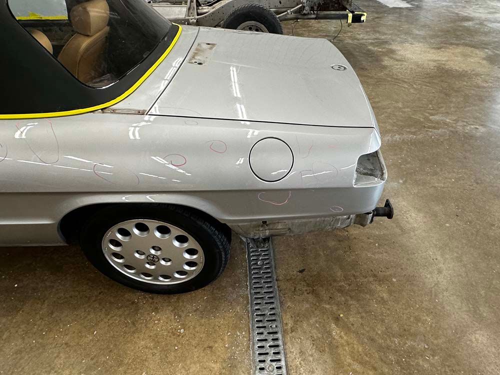 A silver car is parked in a garage next to a drain.