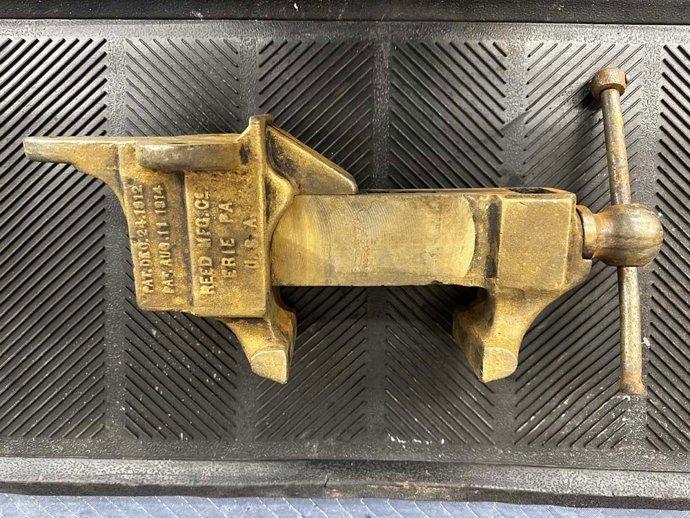 A brass vise is sitting on top of a black mat.