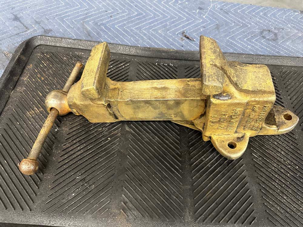 A brass vise is sitting on top of a black mat.