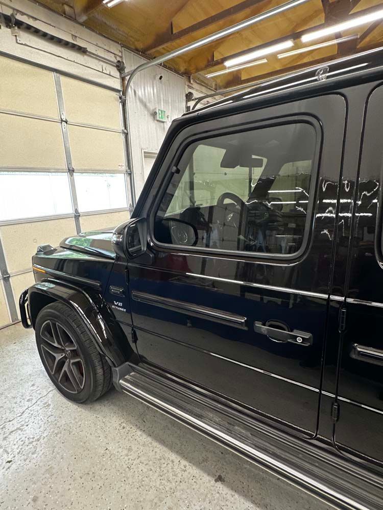 A black jeep is parked in a garage next to a garage door.