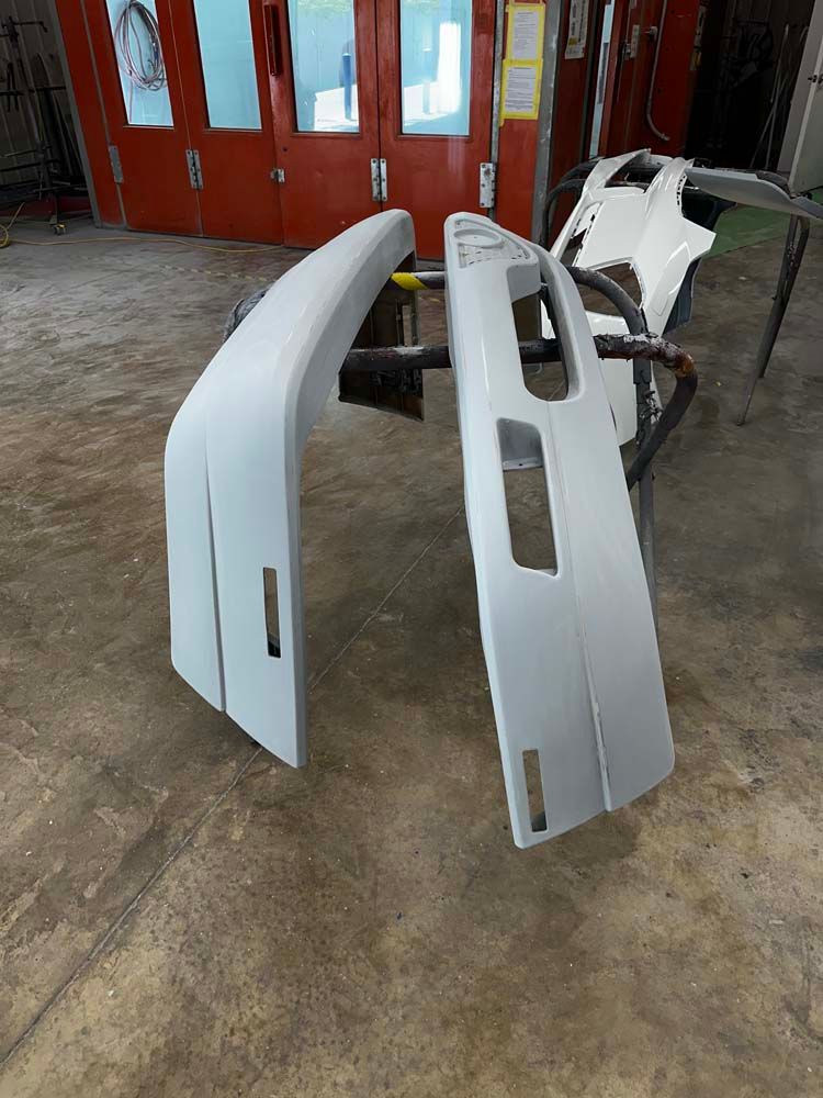 A couple of bumpers are sitting on the floor in a garage.