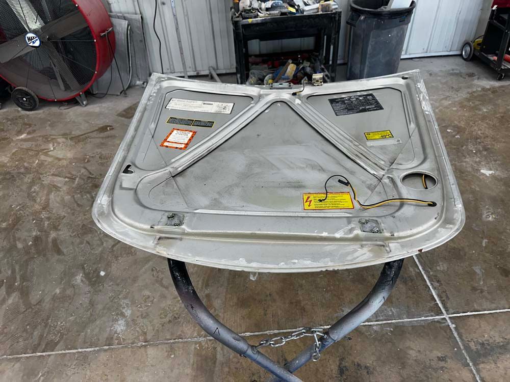The hood of a car is sitting on a table in a garage.