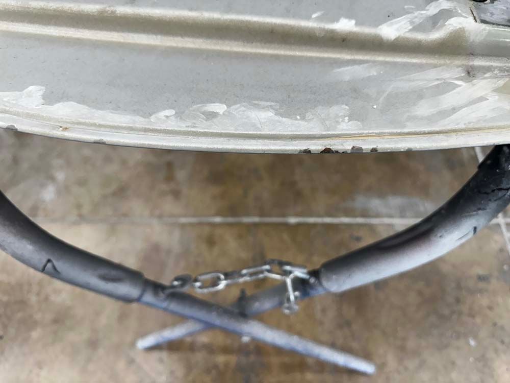 A close up of a car bumper with a hose attached to it.