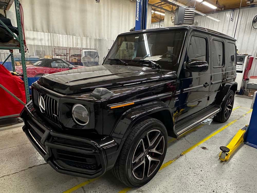A black mercedes benz g63 amg is parked in a garage.