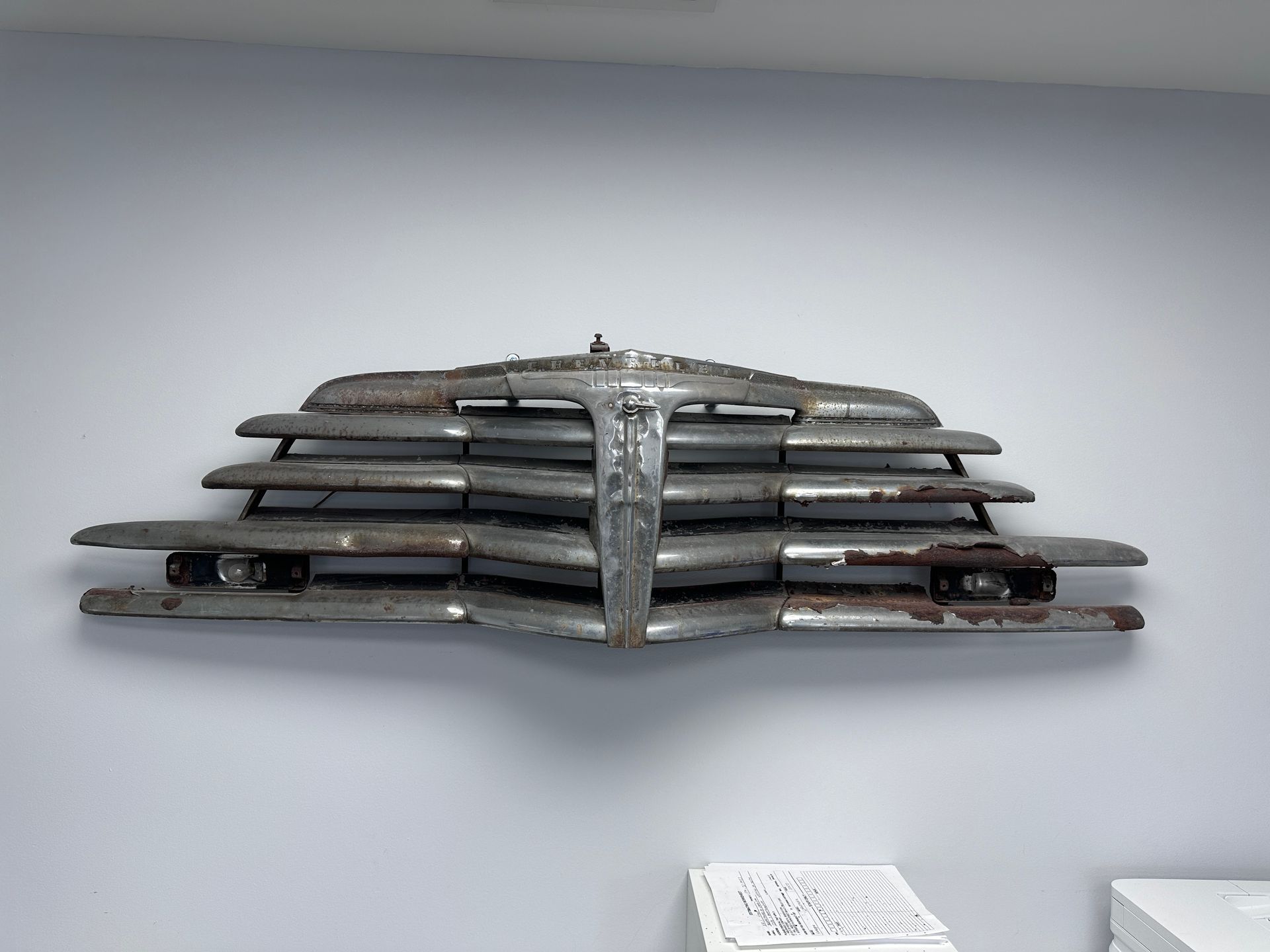 An old car grill is hanging on a wall.