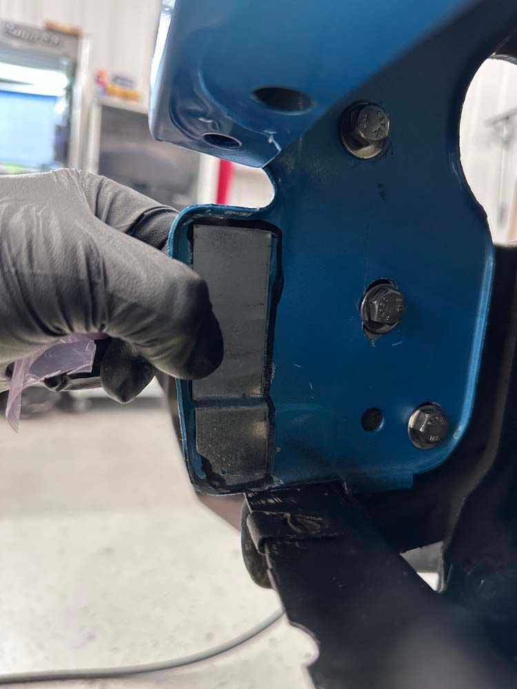 A person wearing black gloves is holding a blue object in their hand.